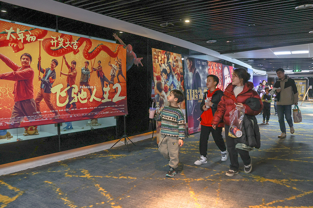 △ 2024年2月16日，在江西赣州一家电影院，观众从春节档电影的宣传展板前走过。